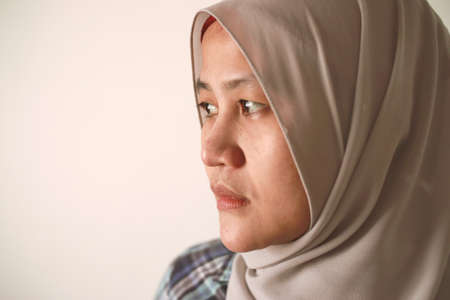 Asian muslim woman wearing hijab looking to the side with neutral expression, diverse people portrait conceptの写真素材