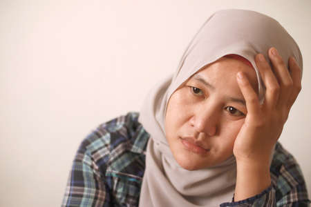 Sad depressed anxiety Asian muslim woman thinking contemplating bad thing happened in her life, stress exhausted feeling down expression, financial or relationship problem conceptの写真素材