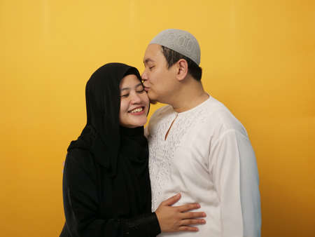 Portait of happy Asian muslim couple smiling, husband and wife hugging and kissing full of love, family conceptの写真素材