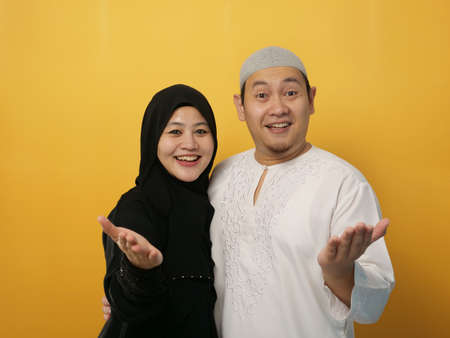 Beautiful happy Asian muslim couple wearing casual clothes smiling friendly offering handshake as greeting and welcomingの写真素材
