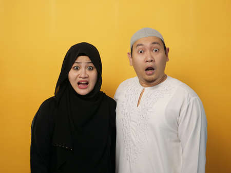 Portrait of happy Asian muslim couple looking at camera, shocked and worried, husband and wife family conceptの写真素材