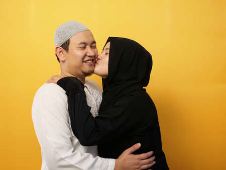 Portait of happy Asian muslim couple smiling, husband and wife hugging and kissing full of love, family conceptの写真素材