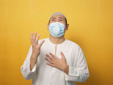 Asian male muslim crying and pray to God against pandemic disease. Stress in lockdown quarantine conceptの写真素材