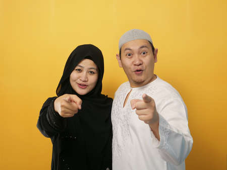 Portait of happy Asian muslim couple smiling and pointing to camera, husband and wife hugging full of love, family conceptの写真素材