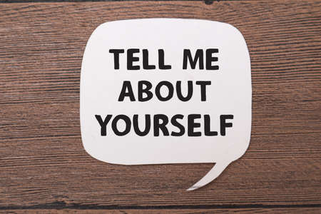 Tell me about yourself, text words typography written on paper against wooden background, life and business motivational inspirational conceptの写真素材