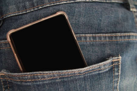 Mobile phone in blue denim jeans pant pocket, pocketing smartphone conceptの写真素材