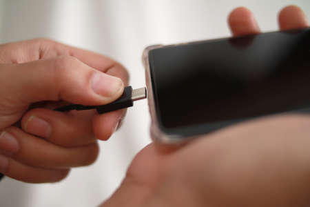 Plug in USB cord cable on smart phone, charging or and data transfer on mobile phone, close upの写真素材