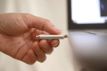 Person inserting plug in flashdisk into usb port in laptop personal computer, data transfer device...