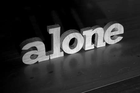 Alone, text words typography written with wooden letter on black background, life and business negativity conceptの写真素材