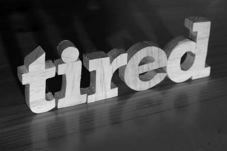 Tired, text words typography written with wooden letter on black background, life and business negativity conceptの写真素材