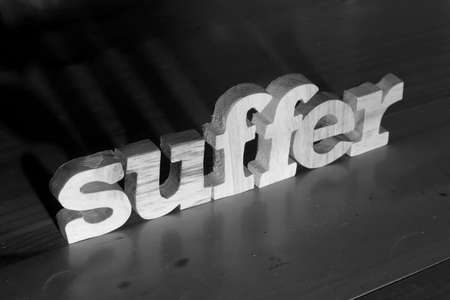 Suffer, text words typography written with wooden letter on black background, life and business negativity conceptの写真素材