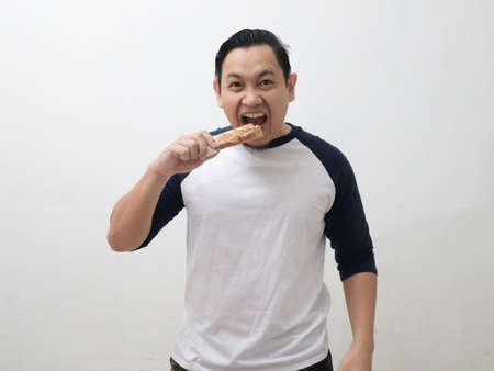 Happy young Asian man eating kebab wrap or shawarma, enjoys delicious foodの写真素材