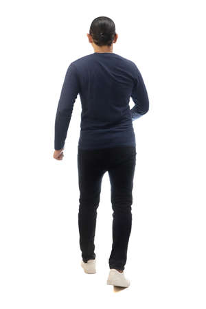 Rear view of a man wearing casual dark blue shirt black denim and white shoes, walking forward, moving with confidence. Full body portrait isolated cut outの写真素材