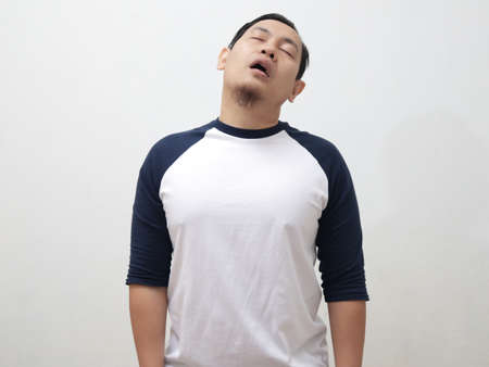 Sleepy tired Asian man slept while standing, over white backgroundの写真素材