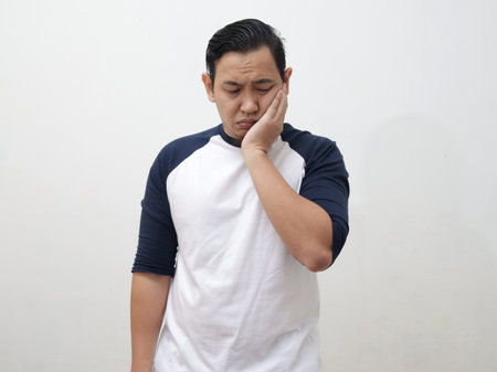 Portrait of Asian man suffering toothache pain, against white backgroundの写真素材