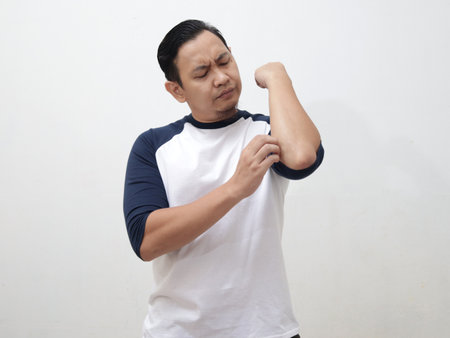 Portrait of young Asian man feel itchy, scratching his body in painの写真素材