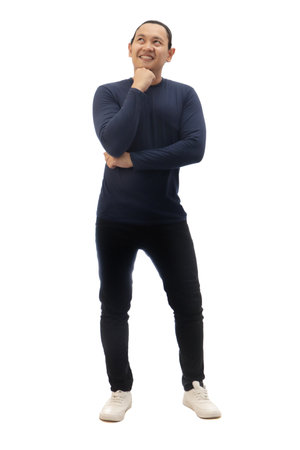 Man wearing casual blue shirt black denim and white shoes, looking up and smiling, thinking good idea. Full body portrait isolated cut outの写真素材