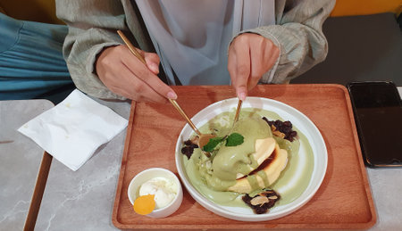 Woman having breakfast at cafe, top high angle view of a person slicing fluffy pancake, girl eating her dessert meal at restaurantの写真素材
