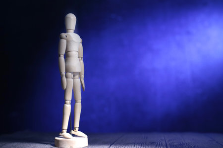 Wooden man doll standing still under the light, againt blue backgroundの写真素材