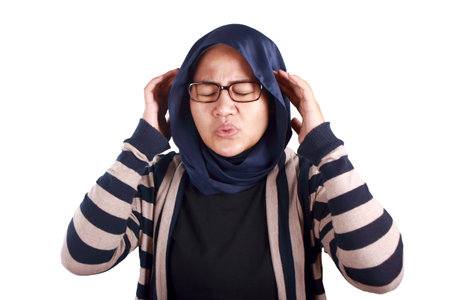 Frustrated stress Asian muslim woman hold her head, depressed anxiety gesture, headache pain expression, isolated on whiteの写真素材