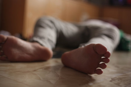 Barefoot man lying on floor, unconscious or dead, drugs overdose suicide, stroke heart attack health issue, or murder victim conceptの写真素材