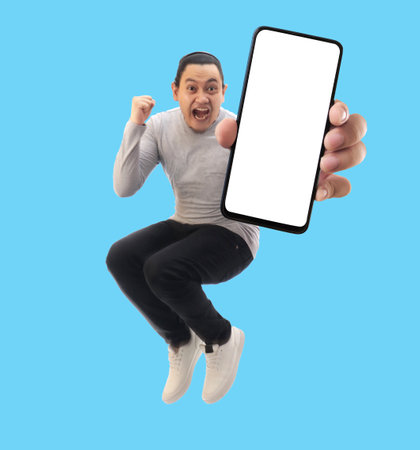 Young Asian man looking to camera, smiling and showing empty blank white copy space phone mock up templateの写真素材