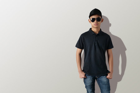 Blank collared shirt mock up template, front view, Asian teenage male model wearing plain black t-shirt over grey background. Polo tee design mockup presentation for printの写真素材