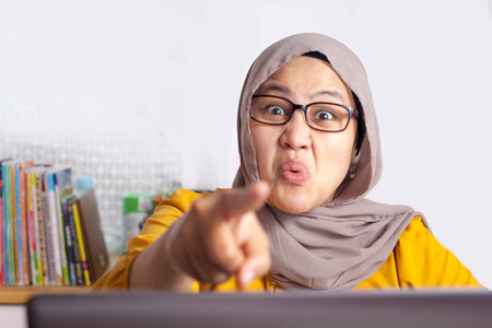 Angry muslim boss businesswoman screaming and pointing shows disappointed gesture for her staff employee worksの写真素材