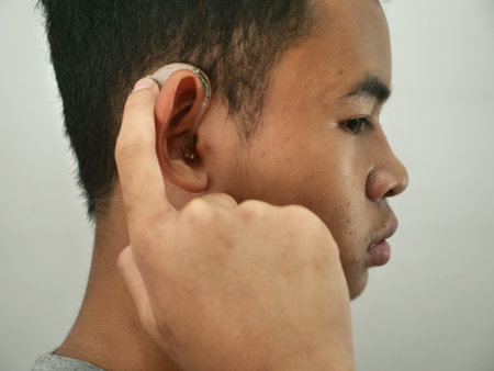 Portrait of Asian boy wearing hearing aid device, close up