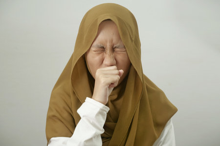Asian muslim teenage girl wearing hijab cough, respiratory health problem, medical disease health care conceptの写真素材