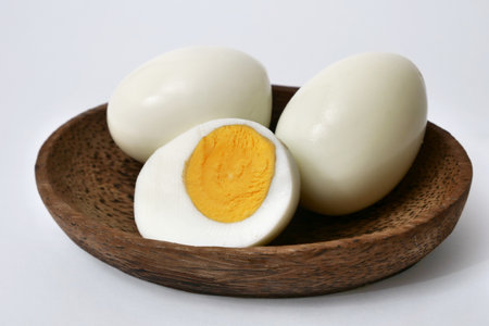 Hard boiled peeled chicken egg sliced in half, served in wooden bowlの写真素材