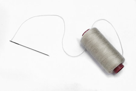 Grey thread and needle over white backgroundの写真素材