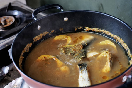 Cooking fish curry, gulai or pindang ikan patin. Delicious Asian dish. Boiling in cauldron