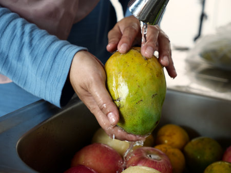 Asian muslim woman washing cleaning fruits in kitchen sink, food preparationの写真素材