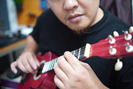 Asian man playing ukulele at home, anonymous personの写真素材