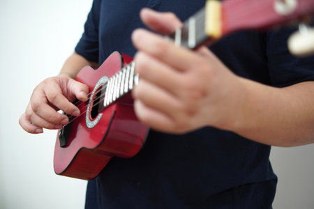Asian man playing ukulele at home, anonymous personの写真素材