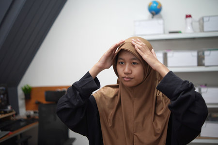 Young Asian muslim woman standing infront of mirror, put her head scarf or hijab onの写真素材