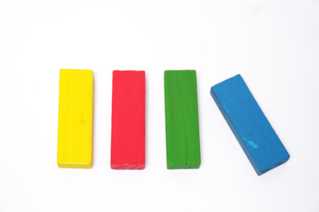 Multi colored wooden toy block on white background, yellow red green and blue