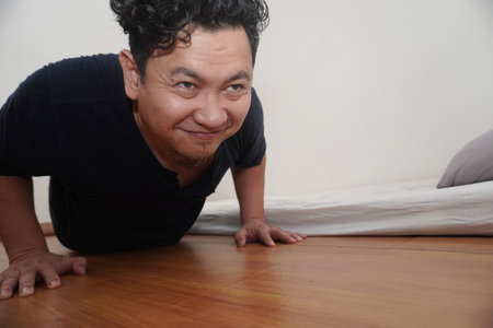 Adult Asian man doing push ups in his bed room, exercise after waking up in the morning