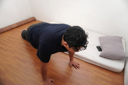Adult Asian man doing push ups in his bed room, exercise after waking up in the morning