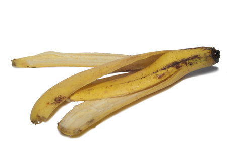 Banana skin peeled, rotten black spotted on yellow, cut out isolated on whiteの写真素材