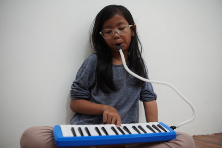 Asian little girl playing pianica, melodica blow organ musical intrument