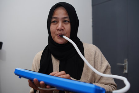 Asian muslim woman wearing hijab playing pianica, melodica blow organ musical intrument