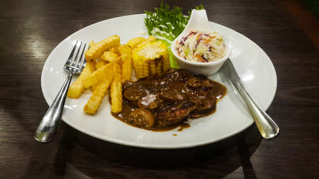 Grill beef with fried fries, Costlow, and vegetable in the white plate on the wooden table.visible noise due to high ISOの写真素材