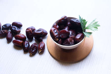 Dried dates fruit in ceramic bowl on wooden table.の写真素材