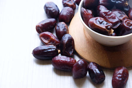 Dried dates fruit in ceramic bowl on wooden table.の写真素材