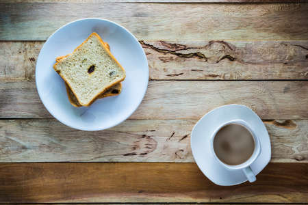Top view shot Hot coffee and Raisin Bread on wood tableの写真素材