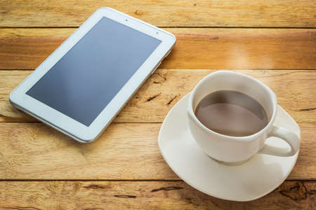 Hot coffee and tablet on wood tableの写真素材