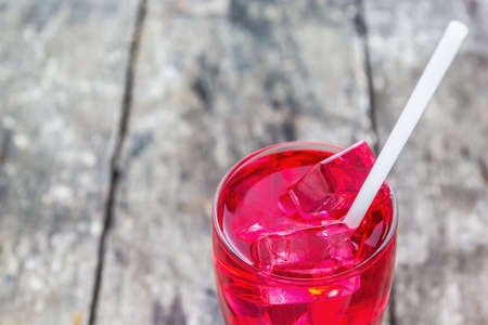 Close up shot Red juice in a glass with ice on wooden tableの写真素材
