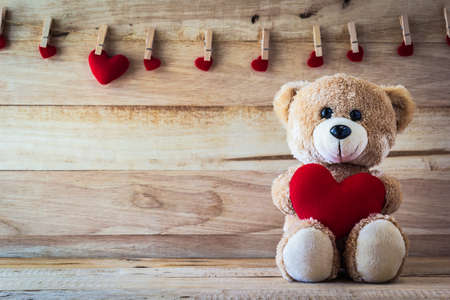 Teddy bear holding a heart-shaped pillowの写真素材